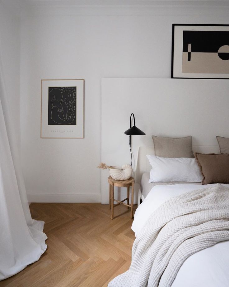 992c33ec-6d5d-4ba0-9e2c-53cdca98ee3a Minimalist bedroom with white bedding, abstract art, and cozy decor on a hardwood floor. | Sky Rye Design Minimalist bedroom with white bedding, abstract art, and cozy decor on a hardwood floor.
