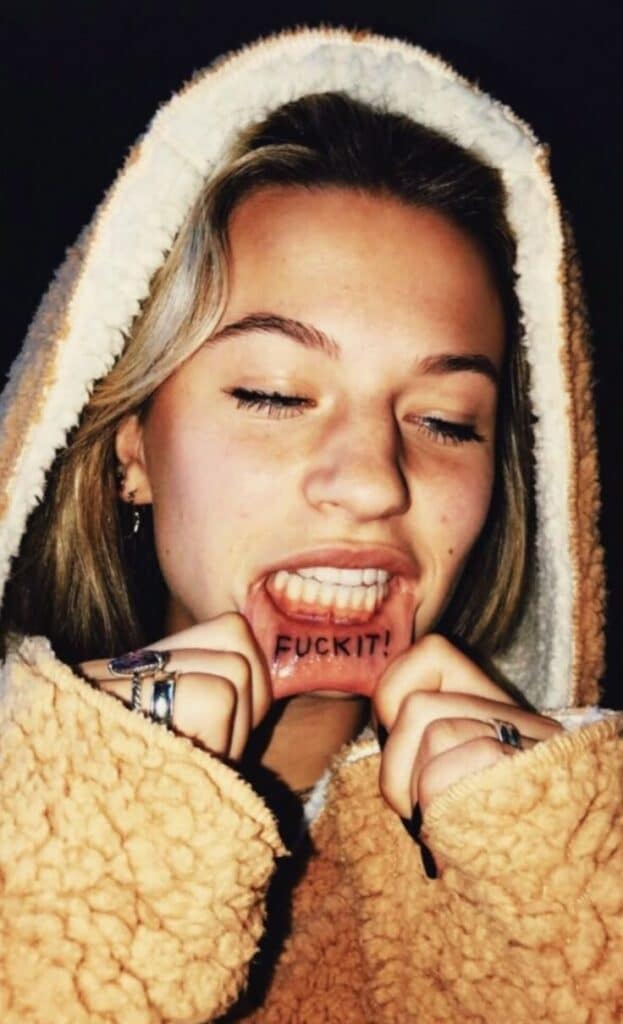 99c27110df97c34f3d0ec8e6f42167da Person showing inner lip tattoo with the words F**k it while wearing a hoodie. | Sky Rye Design Person showing inner lip tattoo with the words F**k it while wearing a hoodie.