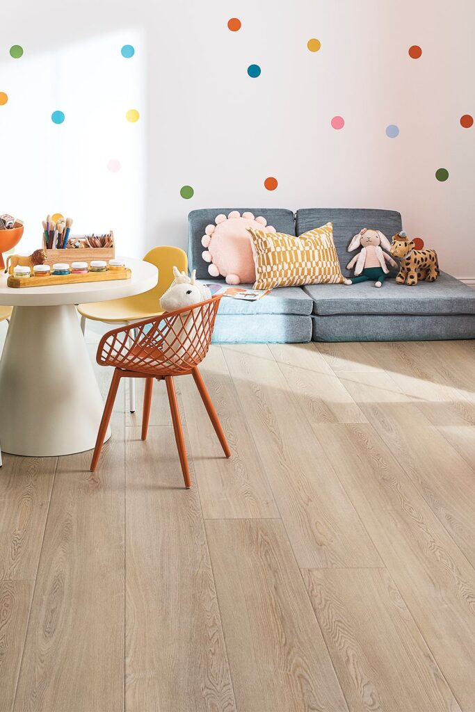 9fd0e85e033594117ef7298491dc2d7d Children's playroom with colorful wall decals, wooden floor, cozy sofa with toys, and a craft table with chairs. | Sky Rye Design Children's playroom with colorful wall decals, wooden floor, cozy sofa with toys, and a craft table with chairs.