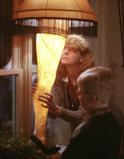 Woman and child admire a leg lamp, iconic scene from A Christmas Story, with vintage lighting and holiday ambiance.