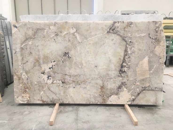 Large polished marble slab with beige and gray patterns, displayed in a showroom, ready for installation.