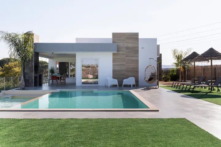 Airbnb _ Portugal Vacation Rentals Places to Stay Modern villa with pool, sun loungers, and lush lawn, ideal for luxury relaxation and outdoor gatherings. | Sky Rye Design Modern villa with pool, sun loungers, and lush lawn, ideal for luxury relaxation and outdoor gatherings.