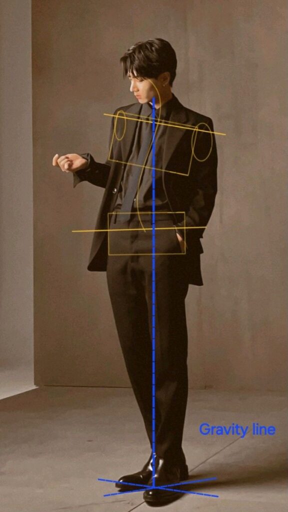 Person in a stylish black suit with gravity line illustration, standing confidently in a studio setting.