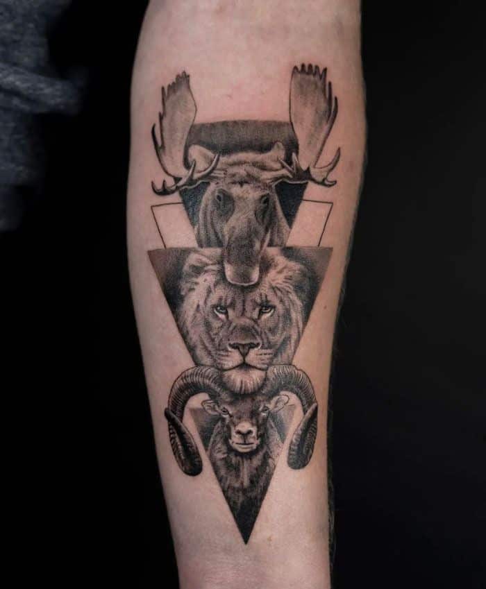 Geometric tattoo with moose, lion, and ram heads on forearm, intricate black and gray design.