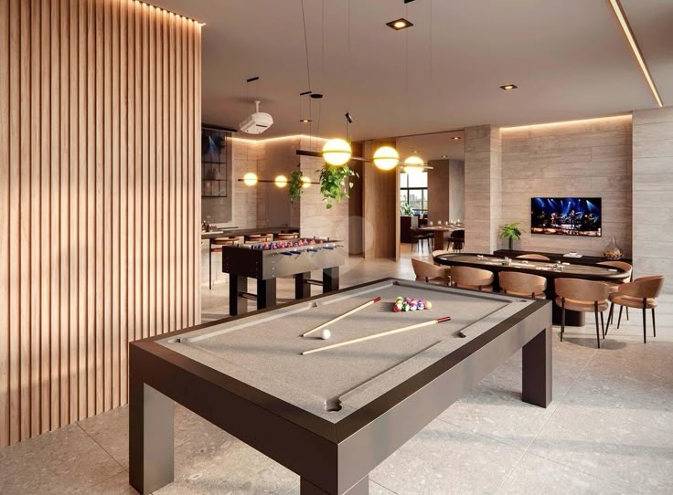 Modern game room with pool and foosball tables, stylish lighting, plants, and a TV setup for entertainment.