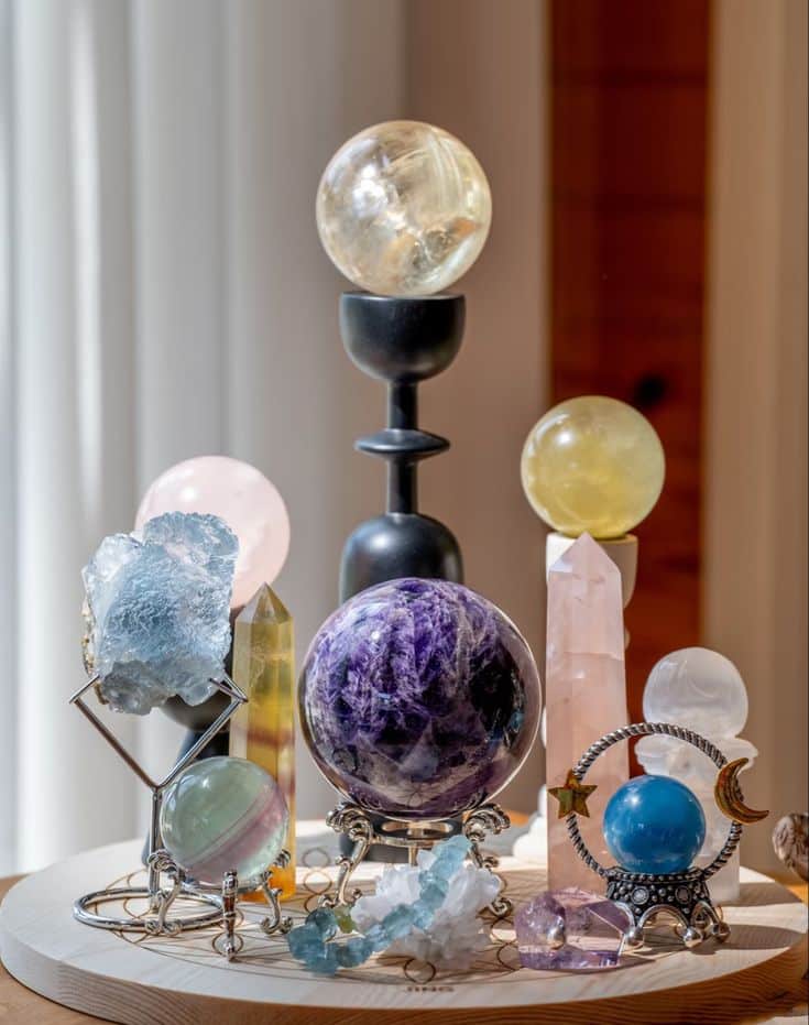 Assorted crystal spheres and towers displayed on decorative stands with natural light.