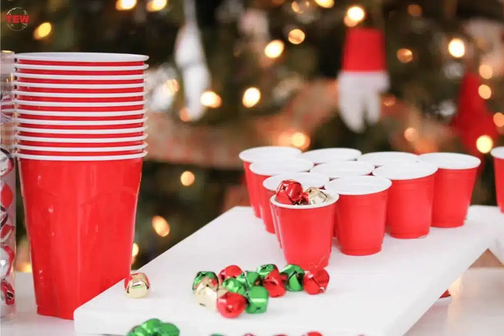 Red plastic cups and colorful jingle bells with festive lights in the background.