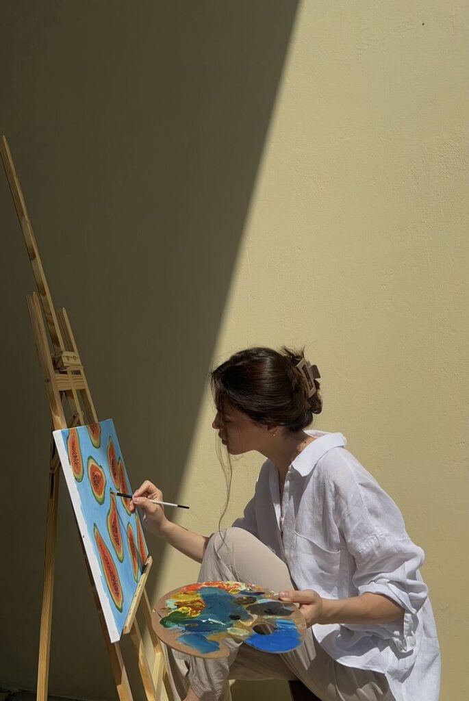 Artistic Inspiration 2 Artist painting colorful abstract art on canvas in sunlight, wearing a white shirt, holding a palette. | Sky Rye Design Artist painting colorful abstract art on canvas in sunlight, wearing a white shirt, holding a palette.