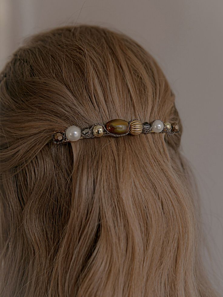Beaded hair accessory on wavy brown hair, featuring pearls and gold accents for an elegant style.