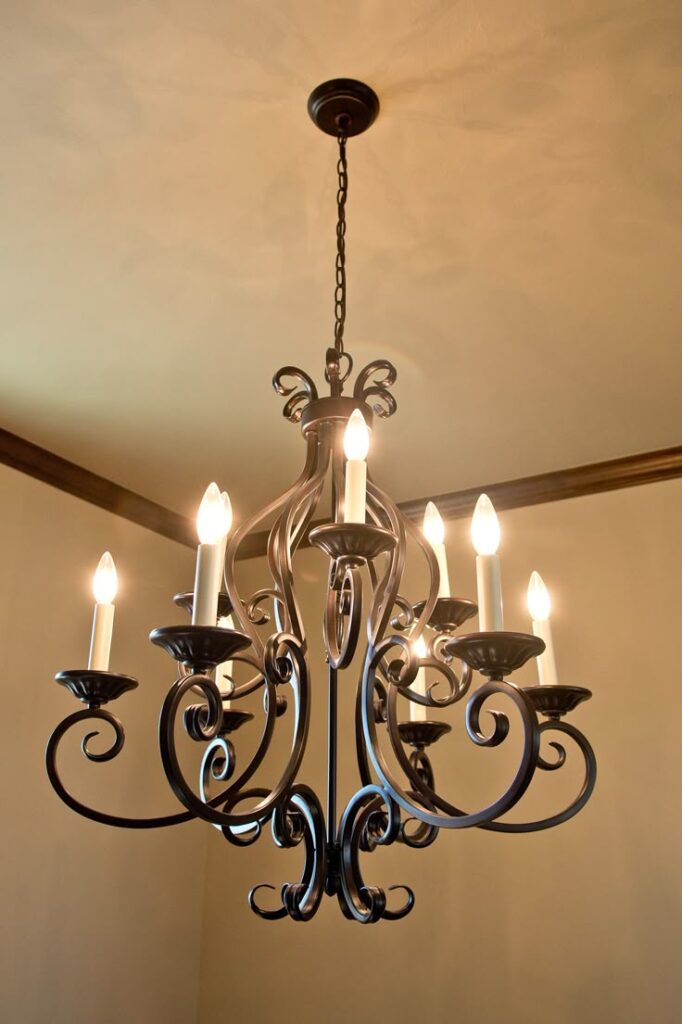Elegant wrought iron chandelier with candle-style bulbs, enhancing classic interior lighting.