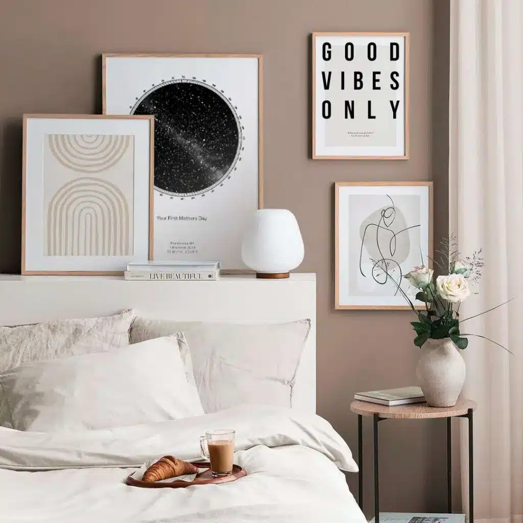 Cozy bedroom with framed art, neutral tones, bedside lamp, vase with flowers, and breakfast tray on bed.