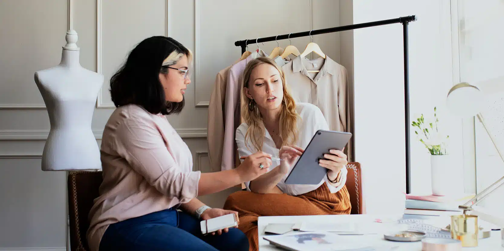 Best_Online_Personal_Styling_Service-ownmuse-3 Two women discussing fashion designs with a tablet in a modern studio setting. | Sky Rye Design Two women discussing fashion designs with a tablet in a modern studio setting.
