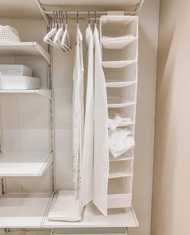 Organized closet with white hangers and fabric storage shelves, maximizing vertical space for efficient storage.