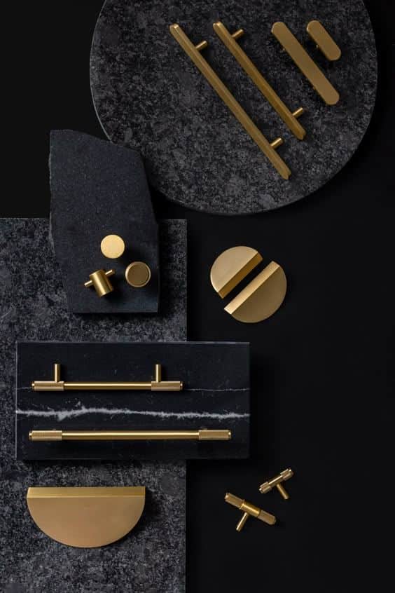 Gold cabinet handles and knobs on dark stone slabs, showcasing modern interior hardware design.