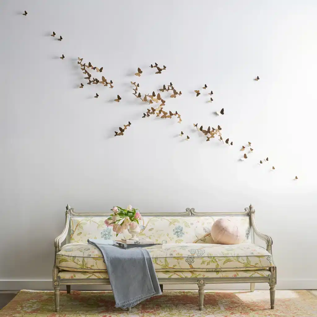 ButterflyWallDecor_ClaireCrowe_install-web Elegant floral sofa with gray throw beneath butterfly wall art on a light wall, creating a serene living room ambiance. | Sky Rye Design Elegant floral sofa with gray throw beneath butterfly wall art on a light wall, creating a serene living room ambiance.