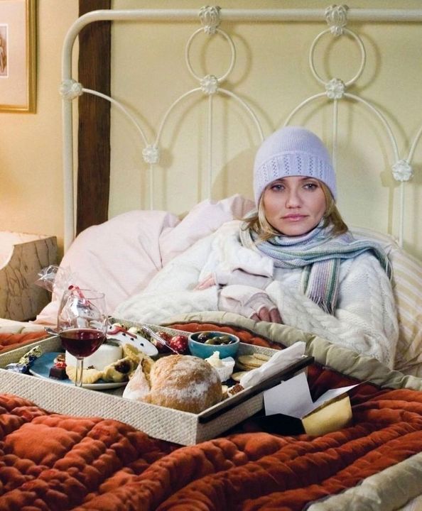Cozy winter morning in bed with breakfast tray, featuring wine, bread, and fruit, while wrapped in warm blankets.
