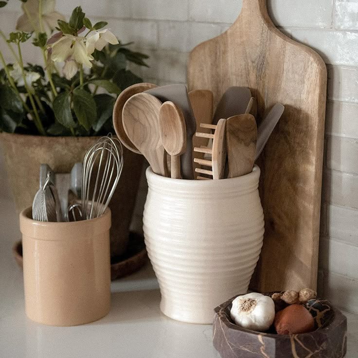 Ceramic Utensil Jar Rustic kitchen utensils in ceramic pots with a cutting board and decorative plants for aesthetic kitchen decor. | Sky Rye Design Rustic kitchen utensils in ceramic pots with a cutting board and decorative plants for aesthetic kitchen decor.
