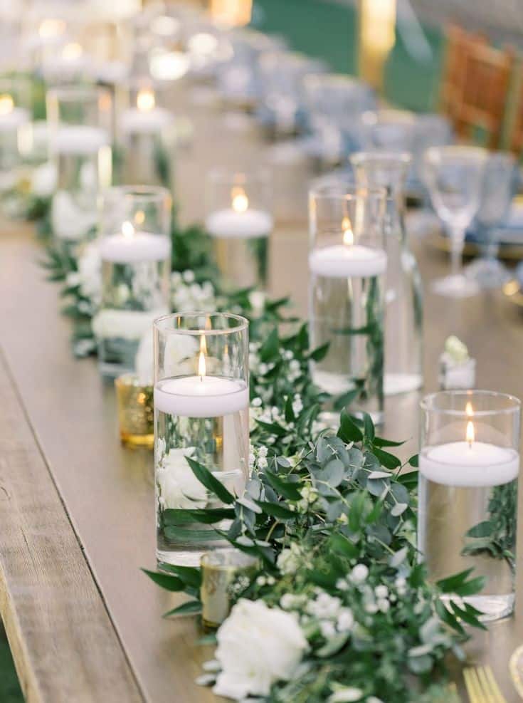 Elegant table setting with floating candles and greenery, perfect for a romantic wedding or event ambiance.