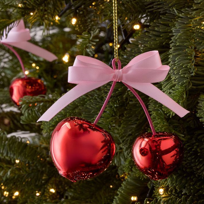 Cherry Capsule Ornaments Cherry Pair Red heart-shaped Christmas ornaments with pink bow on tree. Festive holiday decor with lights. | Sky Rye Design Red heart-shaped Christmas ornaments with pink bow on tree. Festive holiday decor with lights.