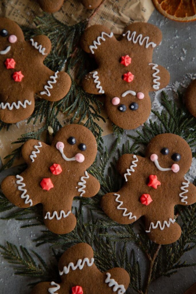 Gingerbread cookies with icing details on festive greenery, perfect for Christmas celebrations.