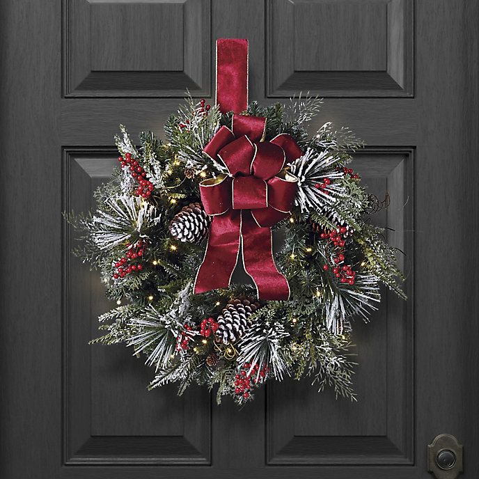 Christmas Cheer Flocked Wreath with LED Lights Red Velvet Bow Festive Christmas wreath with pinecones, red berries, and velvet ribbon, hanging on a dark wooden door. | Sky Rye Design Festive Christmas wreath with pinecones, red berries, and velvet ribbon, hanging on a dark wooden door.