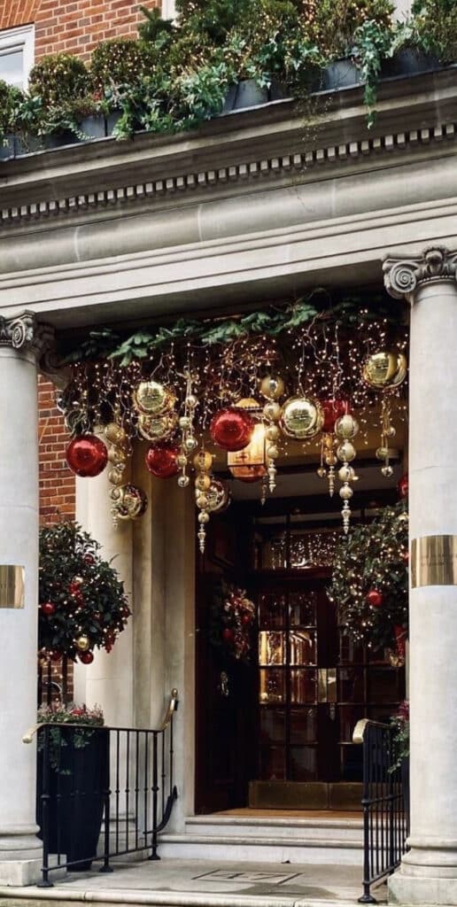 Christmas Dinning Room and Front Porch Setups - How should yours stand out_ HolidayLooks Elegant holiday entrance with red and gold ornaments, festive garland, and twinkling lights. | Sky Rye Design Elegant holiday entrance with red and gold ornaments, festive garland, and twinkling lights.