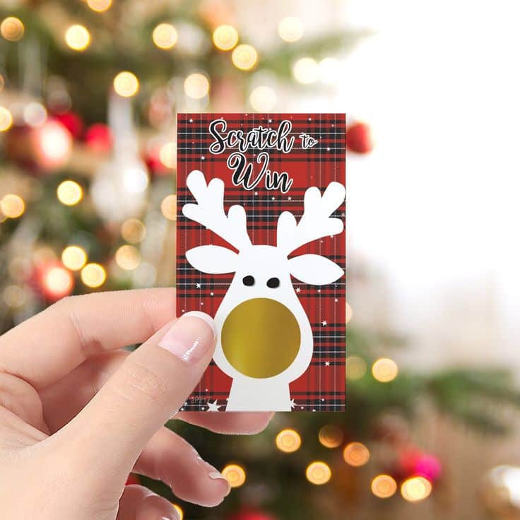 Hand holding reindeer-themed scratch card with festive background, perfect for holiday giveaways.