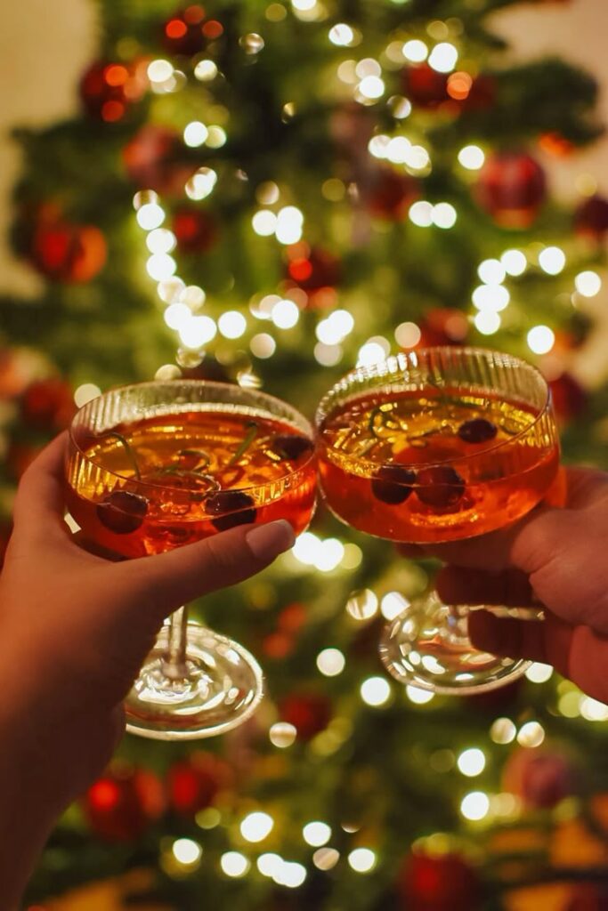 Festive cheers with cocktails in front of a beautifully lit Christmas tree, celebrating the holiday season in style.
