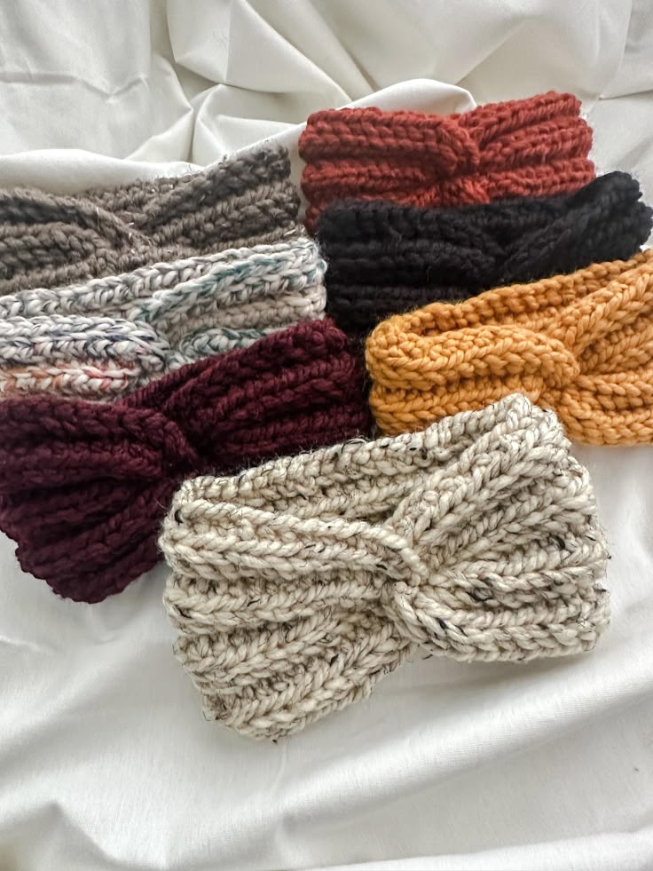 Chunky Knit Crochet Headband _ Ear Warmer Colorful knitted headbands in various hues on a white fabric background, featuring twisted designs for women. | Sky Rye Design Colorful knitted headbands in various hues on a white fabric background, featuring twisted designs for women.