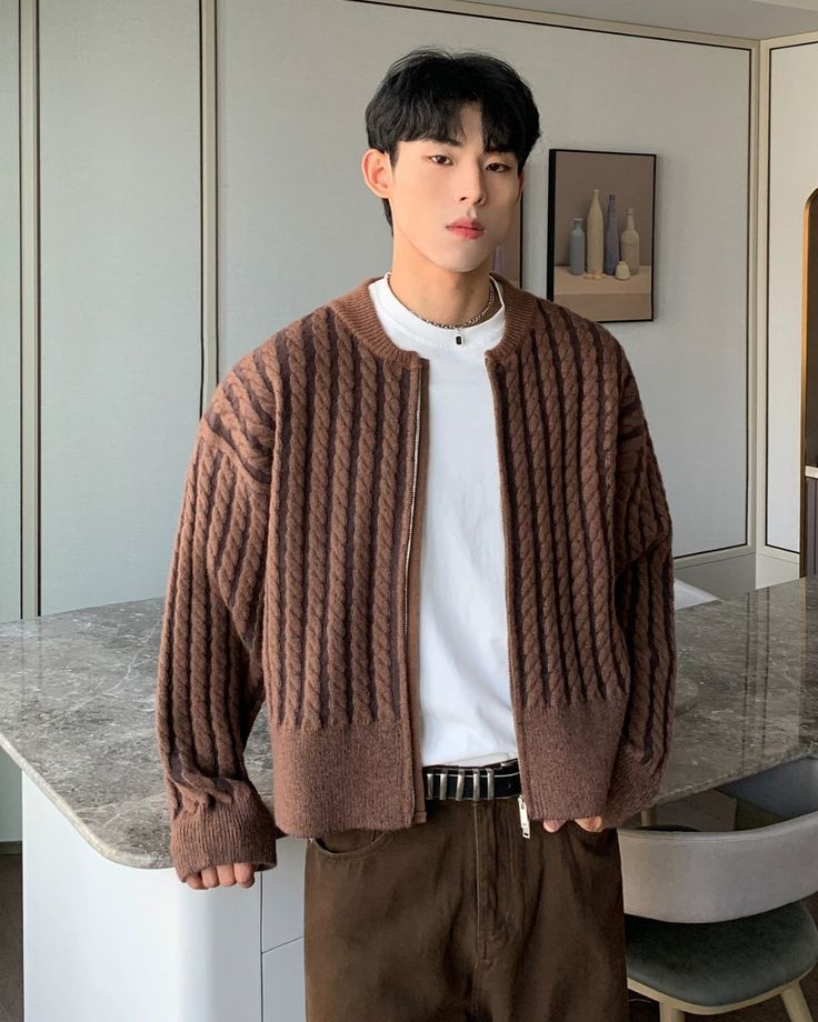 Cui Twisted Knit Zipped Cardigan Discover Young man in a brown textured sweater standing indoors near a marble countertop. | Sky Rye Design Young man in a brown textured sweater standing indoors near a marble countertop.