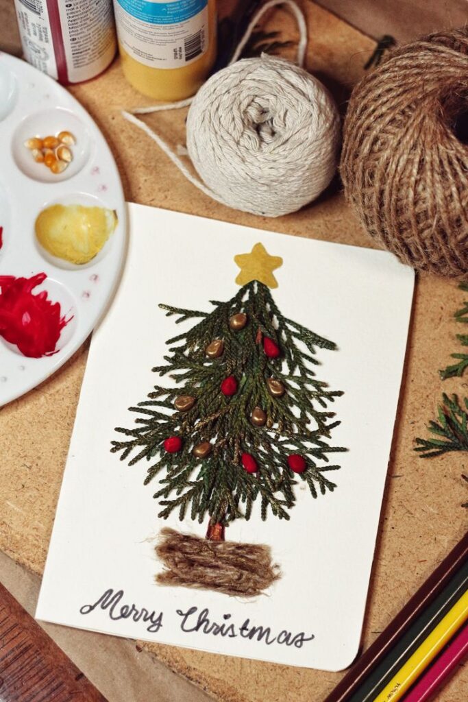 Handmade Christmas card with yarn tree, star topper, and festive decorations on a craft table.