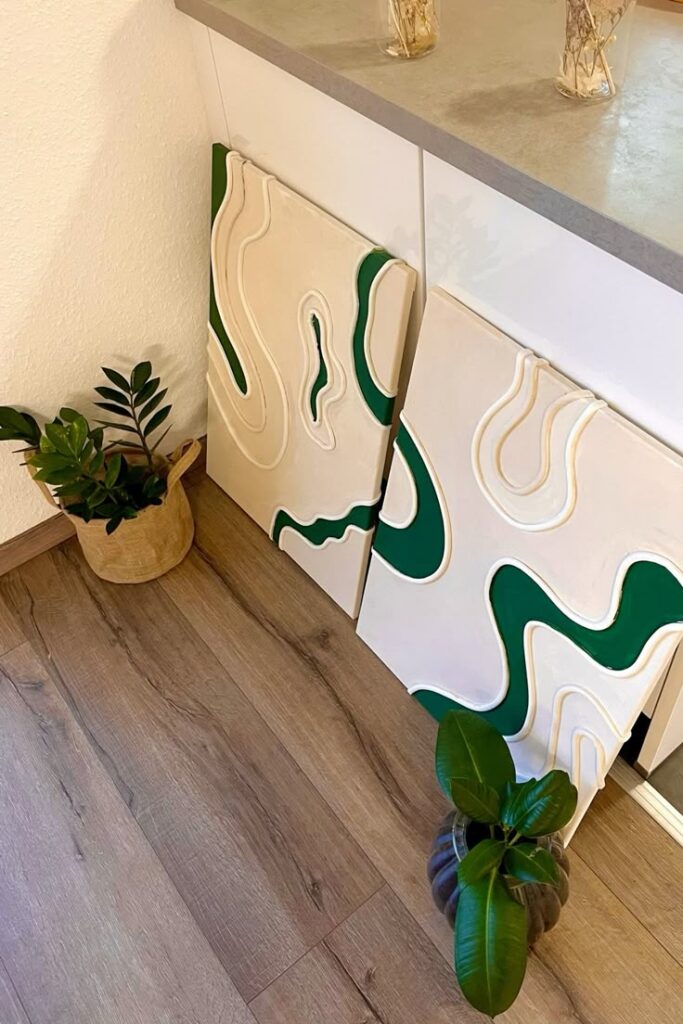 Abstract 3D artwork with green accents beside indoor plants and a modern cabinet on wooden floors.