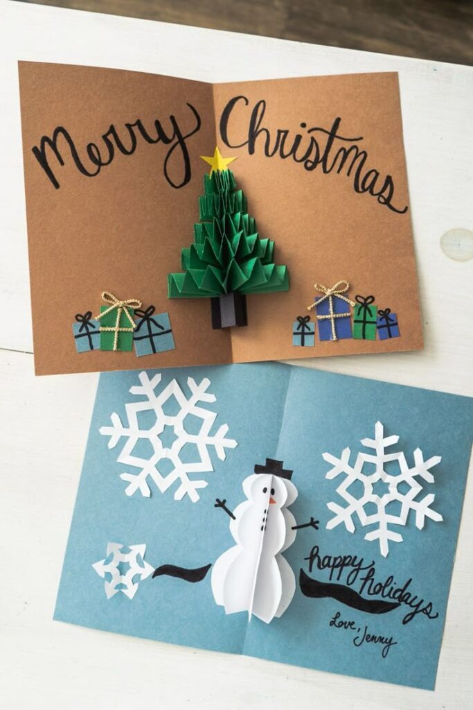 Handmade Christmas cards with 3D designs featuring a tree, gifts, snowflakes, and a snowman.