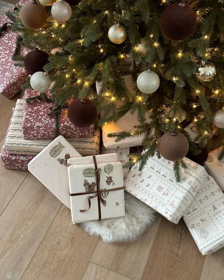 Decoración Christmas tree with lights and ornaments, surrounded by beautifully wrapped gifts in festive paper on a wooden floor. | Sky Rye Design Christmas tree with lights and ornaments, surrounded by beautifully wrapped gifts in festive paper on a wooden floor.