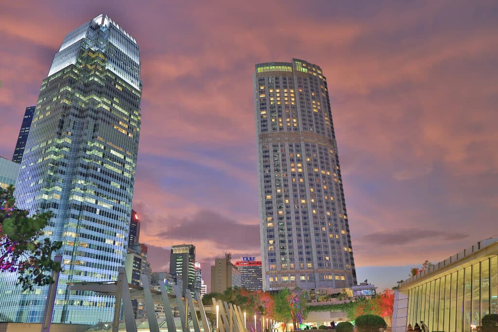 Depositphotos_223742092_XL Two modern skyscrapers under a colorful evening sky in a cityscape setting with illuminated windows. | Sky Rye Design Two modern skyscrapers under a colorful evening sky in a cityscape setting with illuminated windows.