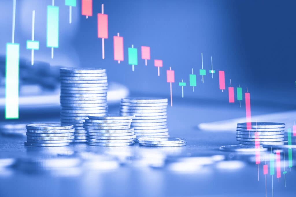 Stacks of coins with a candlestick chart overlay, representing financial growth and investment trends.