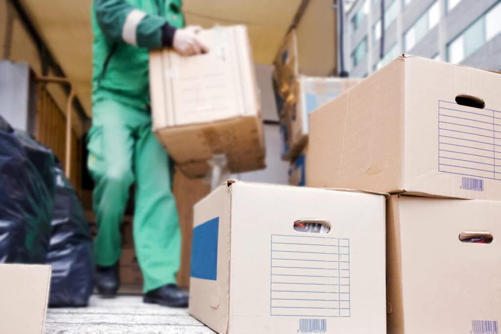 Depositphotos_550452700_XL Worker loading cardboard boxes onto a truck for delivery, focusing on logistics and transportation. | Sky Rye Design Worker loading cardboard boxes onto a truck for delivery, focusing on logistics and transportation.