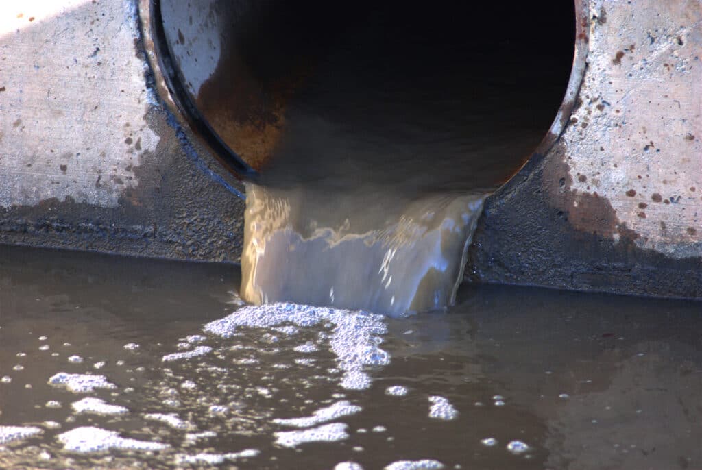 Depositphotos_647227076_XL Industrial wastewater discharge from a concrete pipe into a polluted body of water with visible foam. | Sky Rye Design Industrial wastewater discharge from a concrete pipe into a polluted body of water with visible foam.