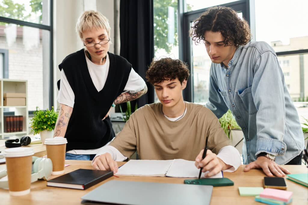 Depositphotos_834987618_L Young professionals collaborating at a desk with notebooks and laptops in a modern office setting. | Sky Rye Design Young professionals collaborating at a desk with notebooks and laptops in a modern office setting.