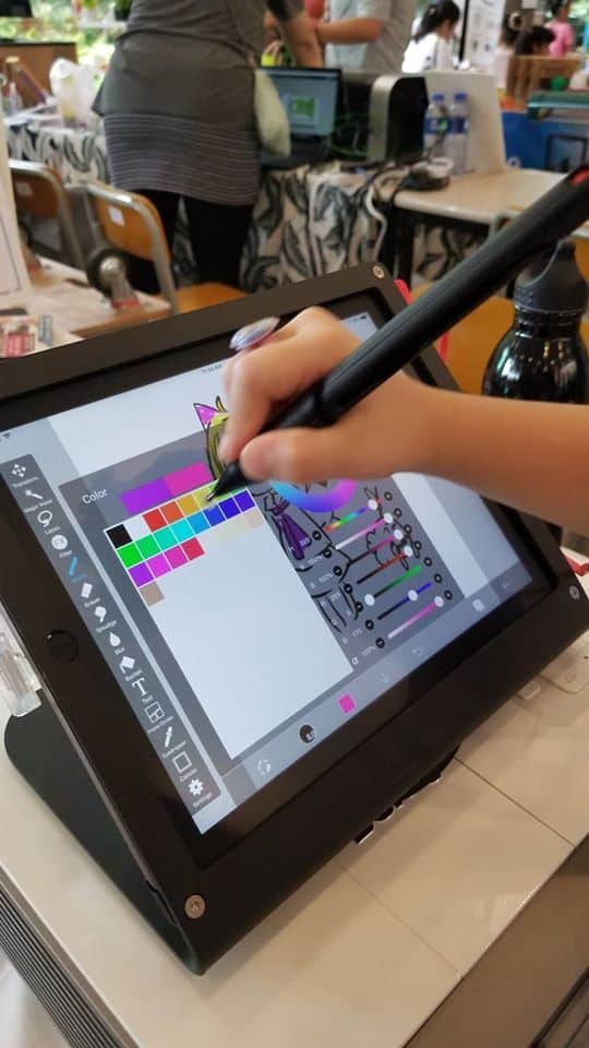 Digital art creation on a tablet with stylus at a tech fair.