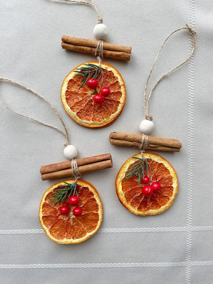 DIY festive ornaments with dried orange slices, cinnamon sticks, and berries on twine, perfect for holiday decorations.