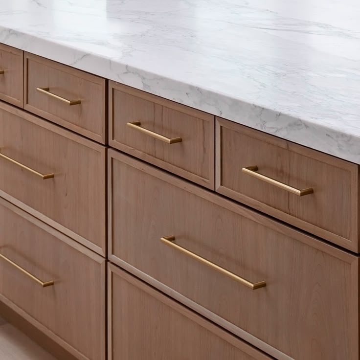Wooden kitchen cabinets with gold handles and marble countertop, emphasizing modern kitchen design and elegance.