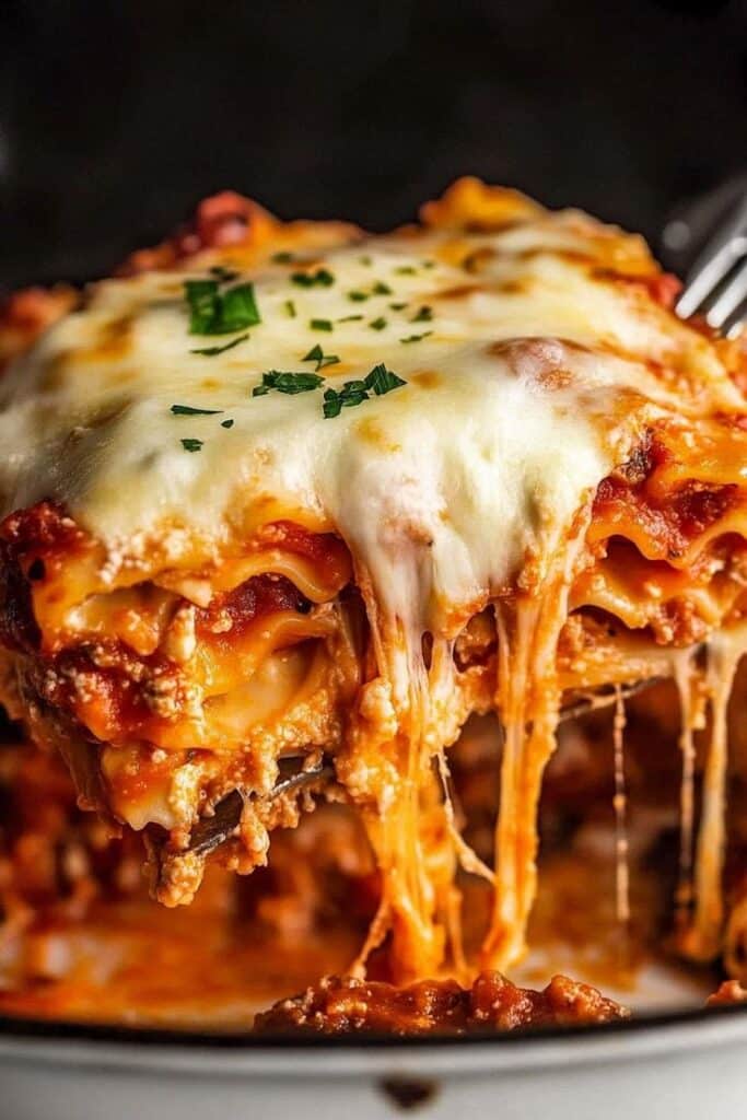 Delicious cheesy lasagna slice with layers of pasta, rich meat sauce, and fresh herbs on a fork.