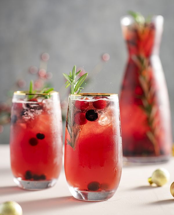 Refreshing cranberry cocktail with rosemary sprigs in tall glasses, perfect for a festive holiday gathering.