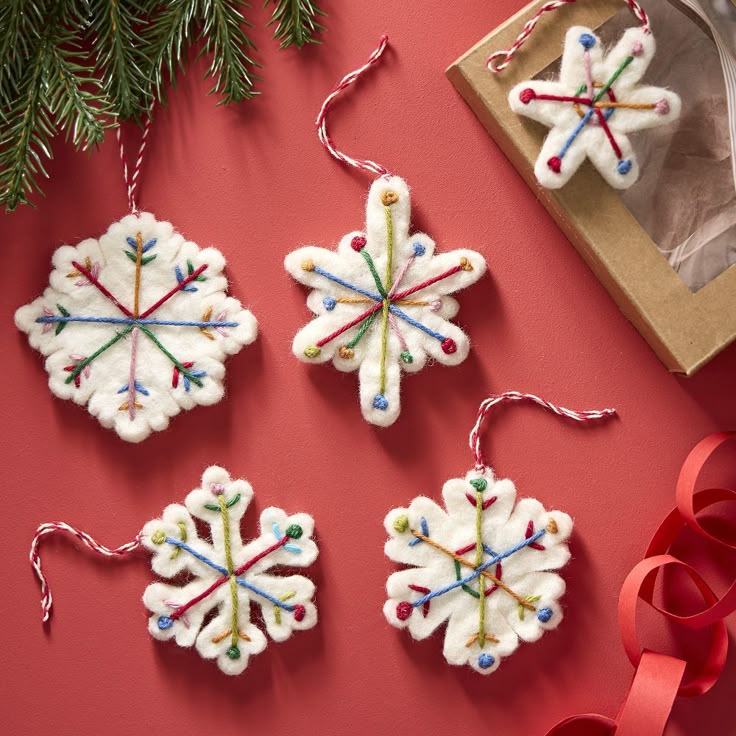 Felt Multicolor Snowflake Ornaments Set of 6 Handmade felt snowflake ornaments with colorful embroidery on red background, surrounded by festive ribbon and greenery. | Sky Rye Design Handmade felt snowflake ornaments with colorful embroidery on red background, surrounded by festive ribbon and greenery.