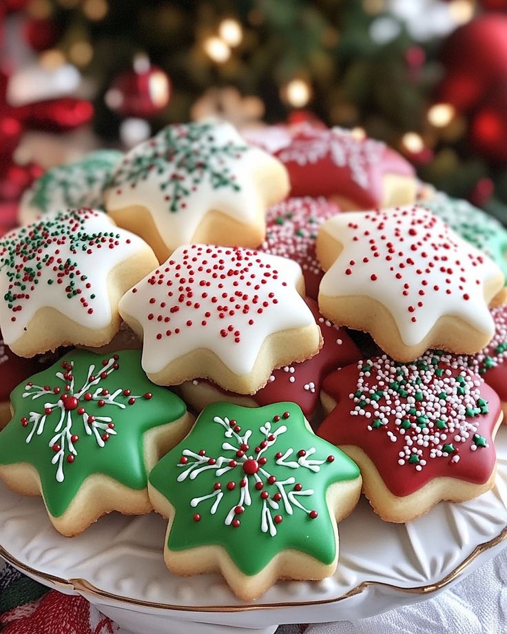 Festive star-shaped Christmas cookies decorated with red, green, and white icing and sprinkles on a plate.