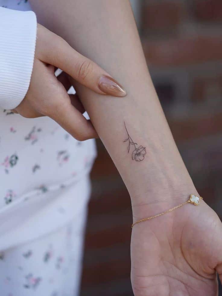 Fineline poppy 💫 Delicate floral tattoo on forearm with gold bracelet, close-up view. Stylish minimalistic body art. | Sky Rye Design Delicate floral tattoo on forearm with gold bracelet, close-up view. Stylish minimalistic body art.