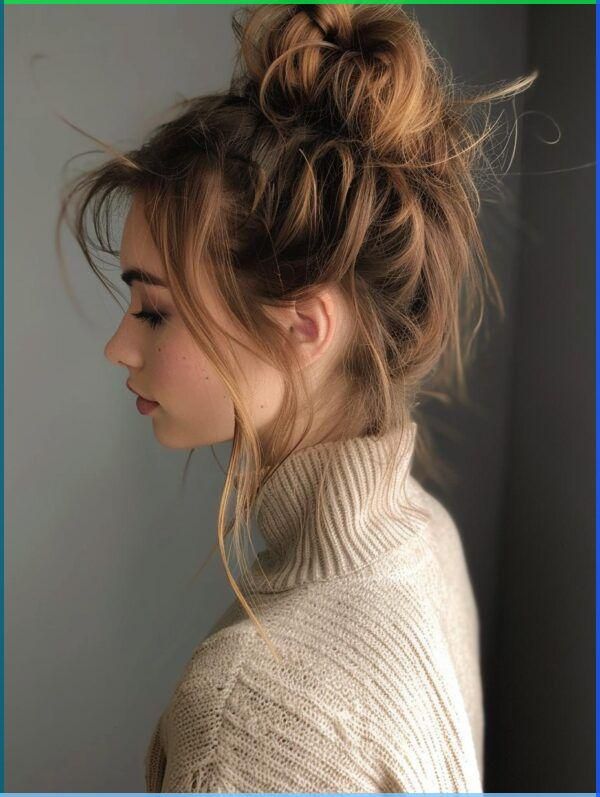 Side profile of a woman with messy bun and cozy beige sweater.