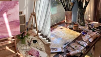 Art studio setup with painting on an easel, brushes, and paints on a table in natural light.