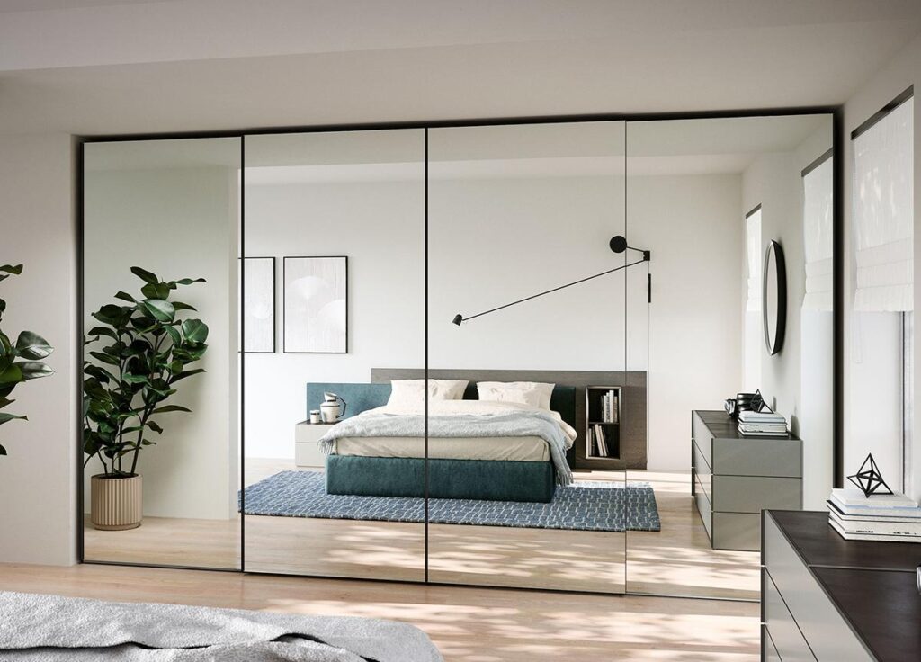 GM-CRYS-06-1 Modern bedroom with mirrored wardrobe, teal bed, and minimalist decor in a cozy, light-filled space. | Sky Rye Design Modern bedroom with mirrored wardrobe, teal bed, and minimalist decor in a cozy, light-filled space.